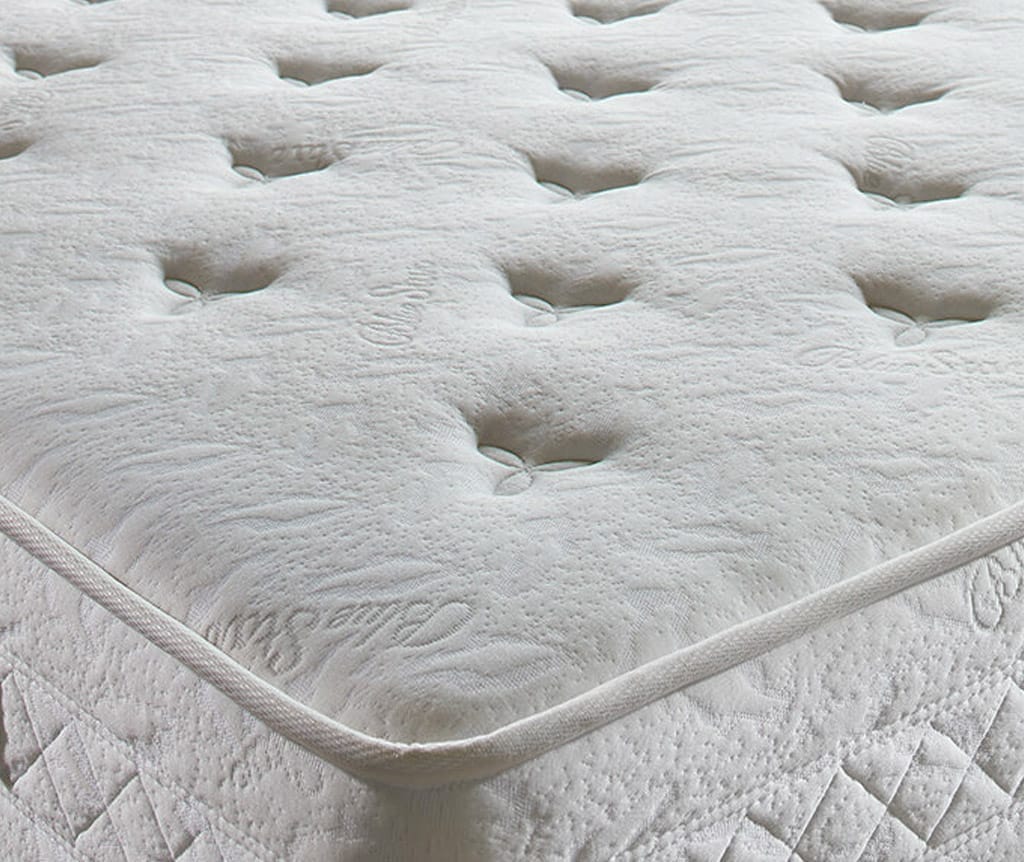 Close up van de gecapitonneerde witte bovenkant en de gestikte rand van het Blue Star matras