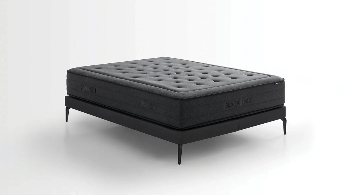 Black Ice matras schuin op een zwart bedframe tegen een witte achtergrond