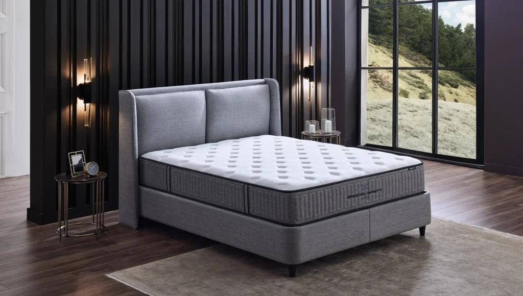 Ergocoil Infinity matras op een grijs gestoffeerd bed in een slaapkamer