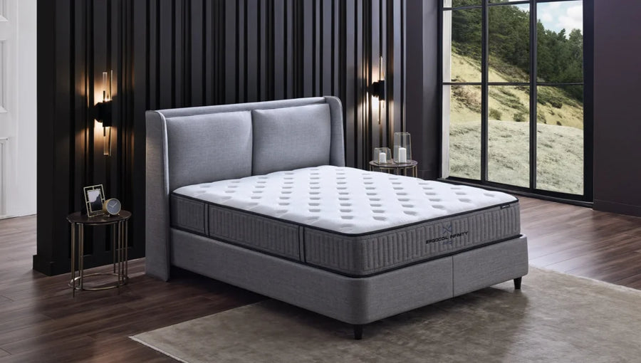 Ergocoil Infinity matras op een grijs gestoffeerd bed in een slaapkamer
