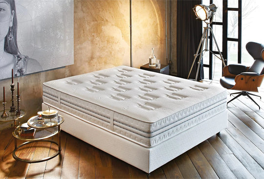 Prestige Prime matras op een wit bed in een loft met gouden wand en leren fauteuil