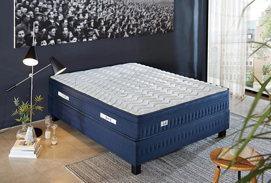 Athletic matras met donkerblauwe zijkant op een blauwe boxspring in een slaapkamer met fotowand