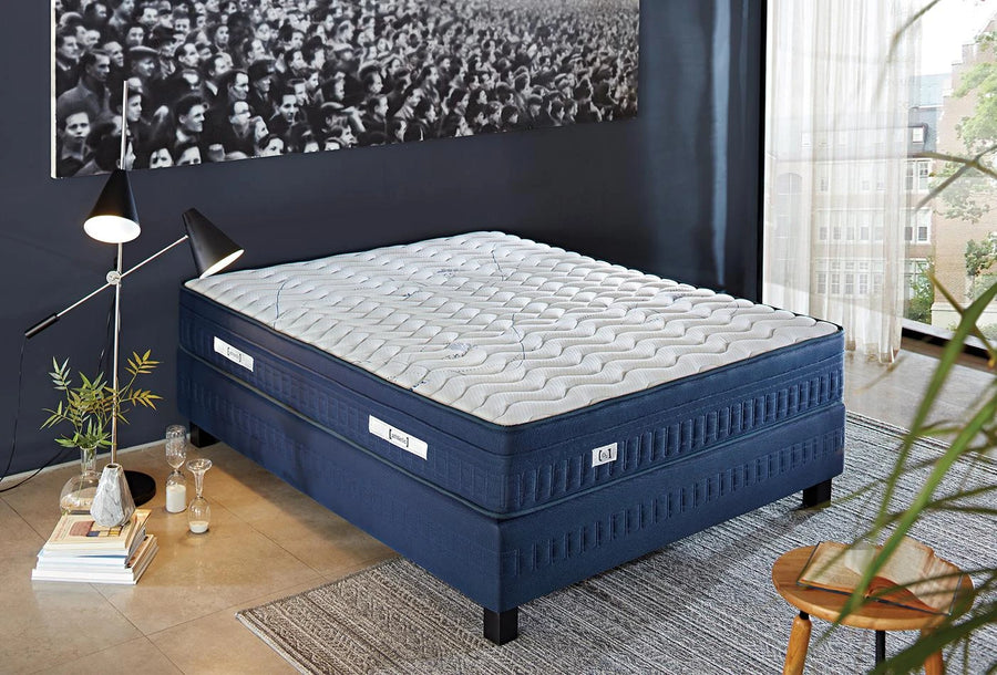 Athletic matras met donkerblauwe zijkant op een blauwe boxspring in een slaapkamer met fotowand
