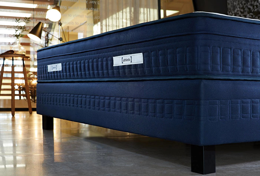 Donkerblauwe boxspring met Athletic matras en houten poten in een loft