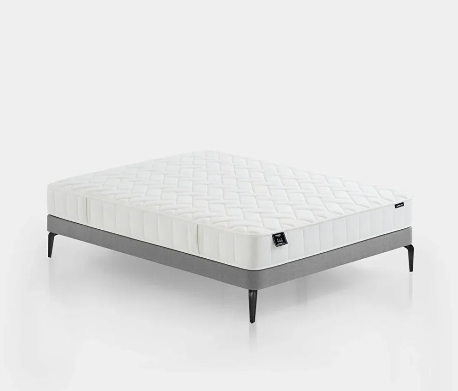 Supreme Star matras met witte gestikte bovenkant op een grijs bedframe met zwarte poten