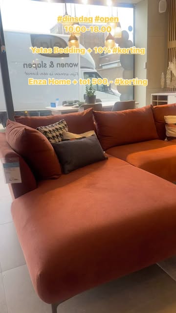 Oranje hoekbank met sierkussens in de showroom