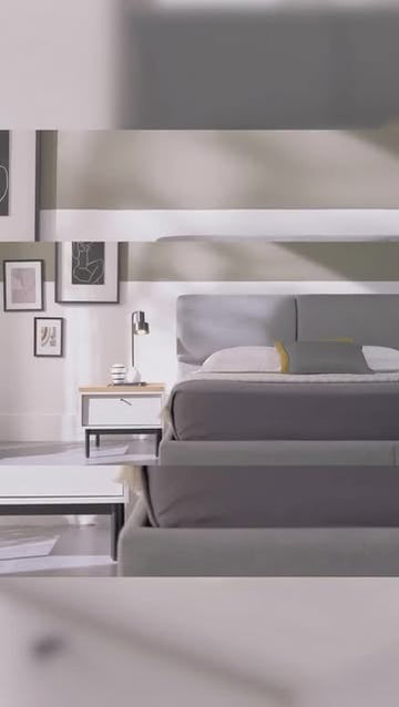 Grijs gestoffeerd bed in een lichte slaapkamer