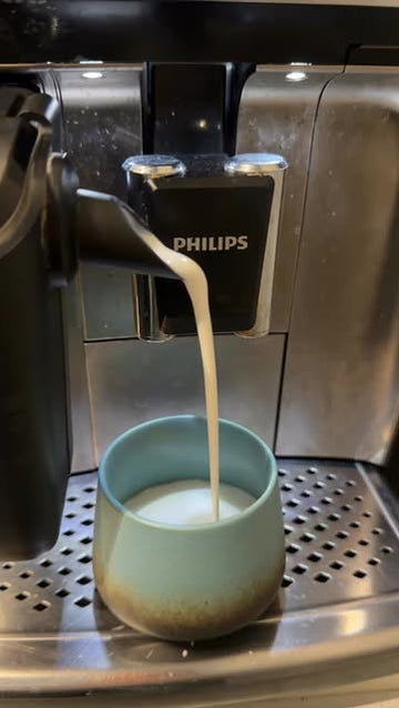 Koffiemachine schenkt warme melk in een groene kop in de showroom